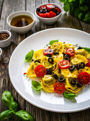 Tortelloni stuffed with prosciutto ham and vegetables on wooden table