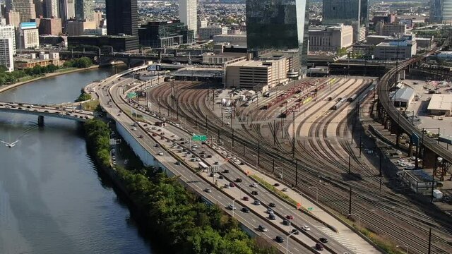 Traffic and transport in Philadelphia. Aerial view of highway on the coast of the Schuylkill River and railways near 30th street station. Panning shot