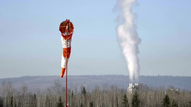 Windsock At Quesnel Airport With Billowing Steam From Industrial Chimney In British Columbia, Canada. - Static Shot