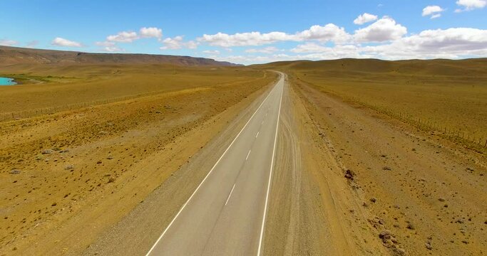 Aerial view of a desert road, in sunny El Chalten, Argentina - rising, drone shot