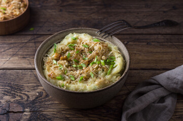 Traditional Irish dish colcannon, mashed potatoes with cabbage and green onions, on top of crispy fried cabbage topping with nuts and spices on wooden table	