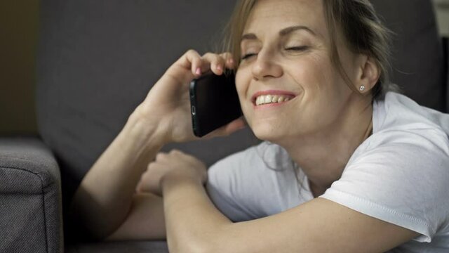 Portrait of a beautiful middle aged woman talking on a cell phone. There is a happy smile on the woman's face. She looks like she's in love.