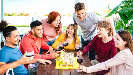 Happy friends having fun together drinking wine at rooftop  on private house party - Young people eating finger food at restaurant - Dinning life style concept on vivid filter