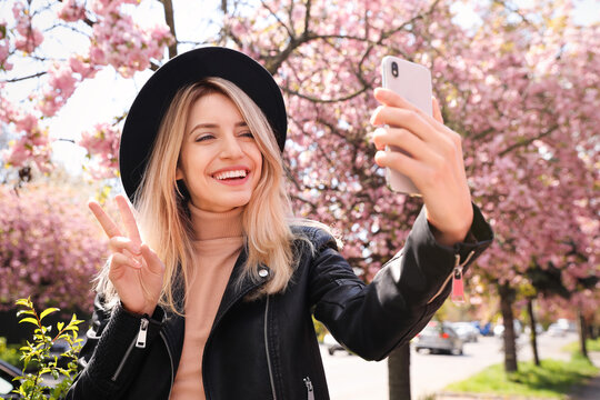 Happy woman taking selfie outdoors on spring day