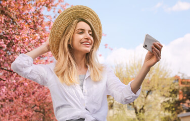 Happy woman taking selfie outdoors on spring day