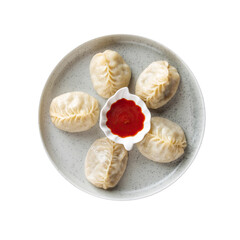 Isolated plate of manti dumplings with red sauce on white