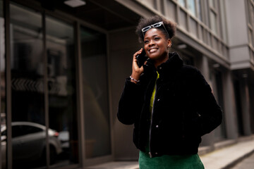Beautiful young woman talking to the phone while walking around town. Young african woman using the phone