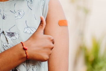 Indian teen giving thumbs up after getting vaccinated and showing bandage on her arm