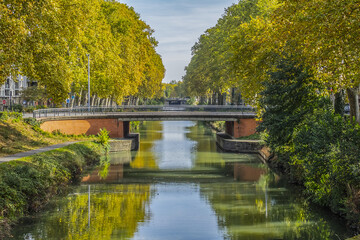 Beautiful autumn views of Canal du Midi (in XVII century - Royal Canal in Languedoc) in Toulouse and trees reflection in water. Toulouse, Haute-Garonne, France.
