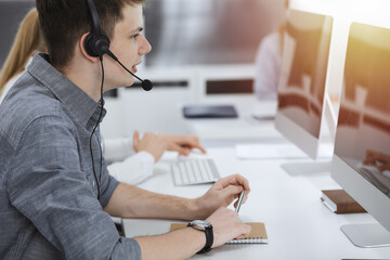 Call center. Group of casual dressed operators at work. Businessman in headset at customer service office. Telesales in business