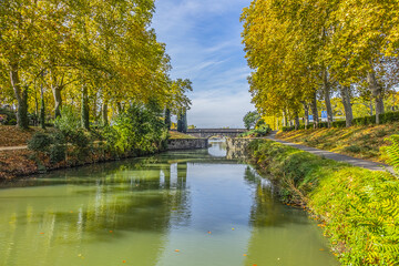 Beautiful autumn views of Canal du Midi (in XVII century - Royal Canal in Languedoc) in Toulouse and trees reflection in water. Toulouse, Haute-Garonne, France. - obrazy, fototapety, plakaty