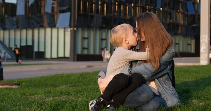 Blond son hugs his mother and says something in her ear. Mother-son relationship, trust. Close bond