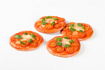 Children mini pizza pink with beet juice added to the dough, with cherry tomatoes, mozzarella and basil on a white background 