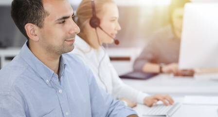 Fototapeta premium Business people working together in modern office. Happy smiling adult businessman using pc computer with colleagues. Teamwork and partnership concept