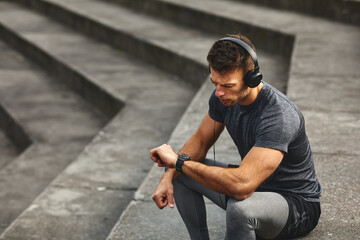 Attractive sport man take a break and check in time results at his smart watch