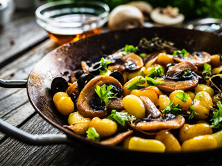 Gnocchi with fried white mushrooms on wooden table
