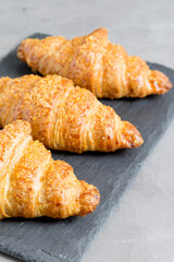 three tasty croissants on black stone background. French food. Close up. Low key