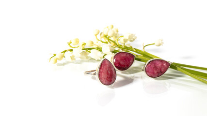 Set of jewelry with luxurious dark pink ruby on a white background. Silver  earrings and ring with precious gem with reflection.