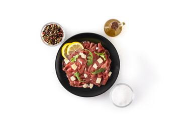 Marbled beef carpaccio on black plate isolated on white background
