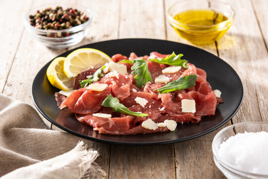 Marbled beef carpaccio on black plate on wooden table