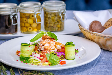 Salad with shrimp, grapefruit, cucumber, radish is served on a large white plate in the restaurant. Close-up. Restaurant menu.