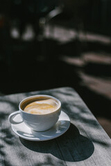 Cup of coffee on a rustic wooden table in a street cafe.