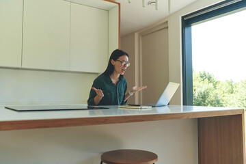 Side view of emotional business woman working from home with laptop and notebook