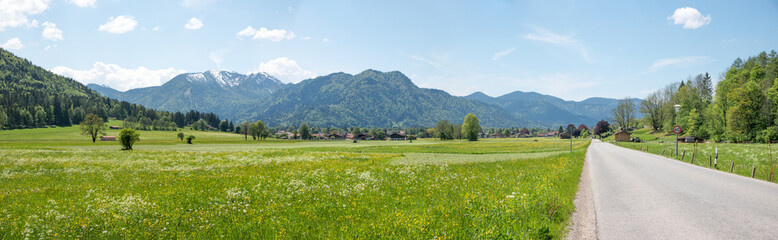 Fototapeta na wymiar country road rural spring landscape Rottach valley, with view to alps and flower meadows, upper bavaria
