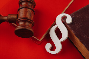 Wooden paragraph symbol is on law book and gavel isolateed on red background