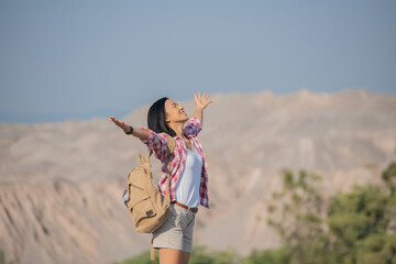 fit young woman hiking in the mountains standing on a rocky summit ridge with backpack and pole looking out over landscape. hiker with backpack relaxing on top of a mountain and enjoying valley view.