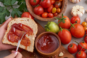 Spreading tomato sauce on toasted bread,female hands smear tomato sauce spread on sandwich bread. preparing lunch or breakfast. tomato sauce with garlic and vibrant green leaves of the italian parsley
