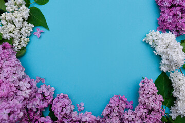 Beautiful purple and white lilac and green leaves on a blue background. Composition of flowers, frame. Mockup for design. copy space for text. Flat lay. view from above.