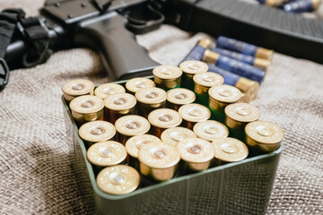 Cartridges of 12 caliber in a plastic box on the background of a semi-automatic gun of the same caliber - 434098782
