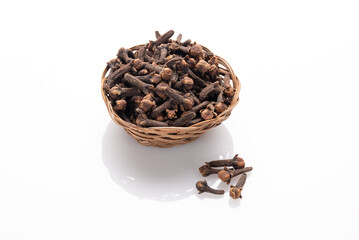 Seasoning cloves in a small basket and handful of cloves next to it isolated on white background