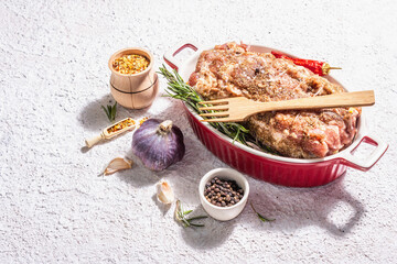 Raw pork roll stuffed with garlic and carrots in a ceramic roasting dish