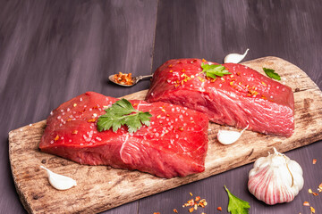 Raw beef steaks on a wooden cutting board