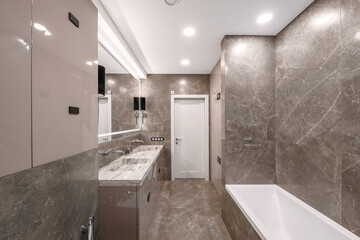 Modern minimalist bathroom beige interior design with marble tiles and glossy beige furniture