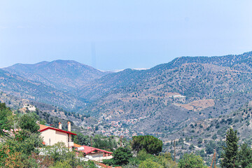 Roofs of Kykkos monastery between green trees on a clear sunny day