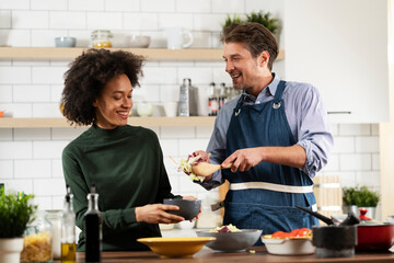Happy smiling couple cooking together. Beautiful woman with curly hair enjoying in kitchen with her husband