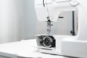 Part of a white professional electric sewing machine, close-up. Internal mechanism of sewing equipment. Repair, maintenance and service
