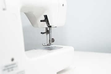 White professional electric sewing machine close-up. Indoors, no people. Cropped image, selective focus
