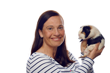 Happy loving woman holding up her pet guinea pig in her hands turning to look at the camera with a friendly smile isolated on white