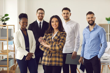 Happy smiling confident female hispanic businesswoman team leader standing together with diverse multiethnic business group in office. Company professional multinational staff portrait