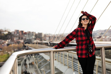 Young woman tourist standing with photo camera on the bridge. Beautiful woman traveling around the city..