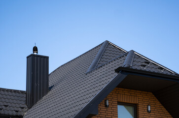 Brown corrugated metal profile roof installed on a modern house. The roof of corrugated sheet. Roofing of metal profile wavy shape. Modern roof made of metal. Metal roofing.