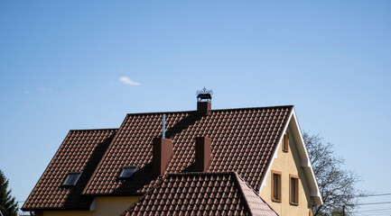 Brown corrugated metal profile roof installed on a modern house with a attic windows. The roof of...