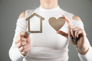 young woman holding a house and a heart.