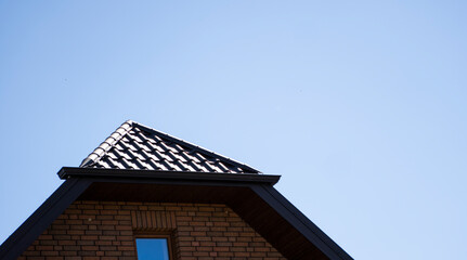 Brown corrugated metal profile roof installed on a modern house. The roof of corrugated sheet. Roofing of metal profile wavy shape. Modern roof made of metal. Metal roofing.