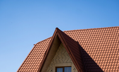 Red corrugated metal profile roof installed on a modern house. The roof of corrugated sheet. Roofing of metal profile wavy shape. Modern roof made of metal. Metal roofing.