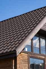 Brown corrugated metal profile roof installed on a modern house. The roof of corrugated sheet. Roofing of metal profile wavy shape. Modern roof made of metal. Metal roofing.